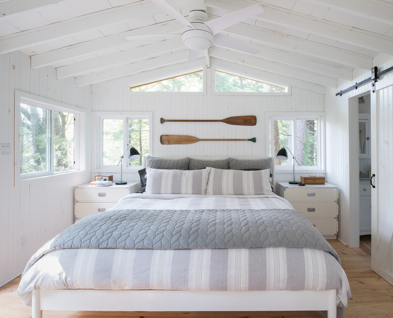 whitewashed coastal bedroom with oars above bed