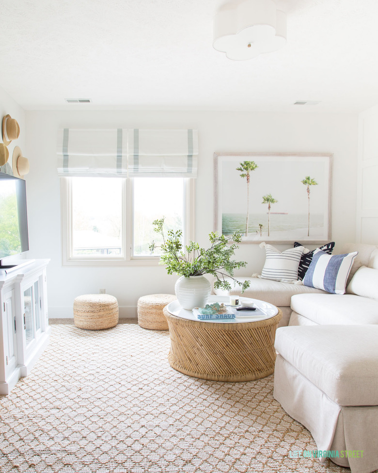 fresh coastal family room with rattan furniture and white roman shades