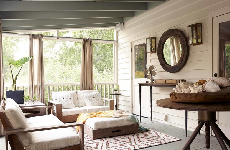 white coastal farmhouse sunroom with wood furniture and patterned rug