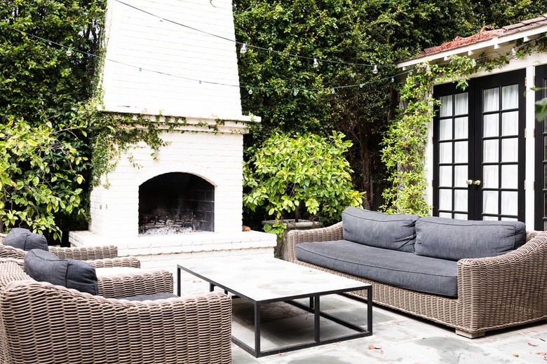 coastal grandmother decor idea for patio with woven outdoor sofas with gray cushions and outdoor fireplace