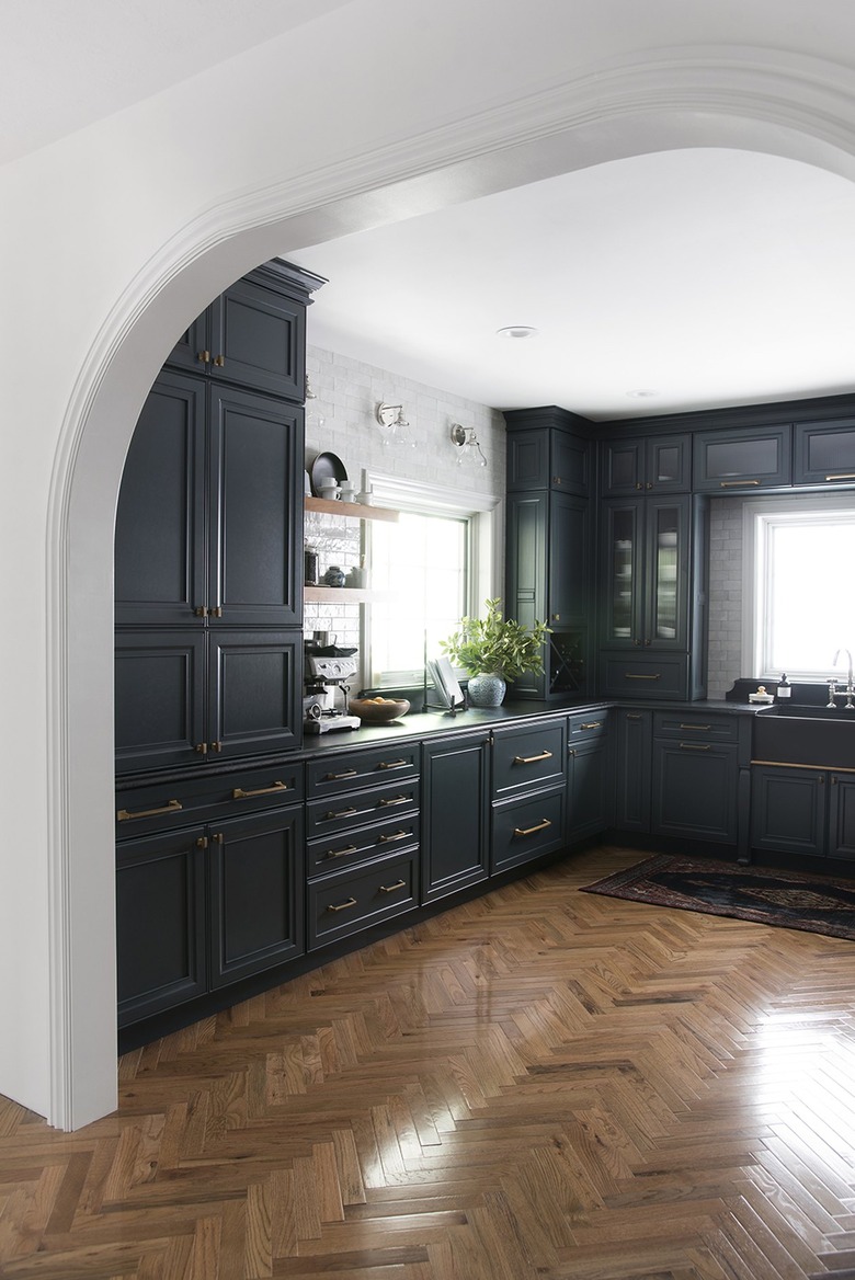 Kitchen with black cabinets, wood floors and white backsplash