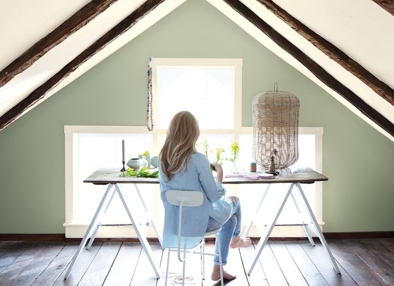 Attic room with light green walls and a woman sitting near the window