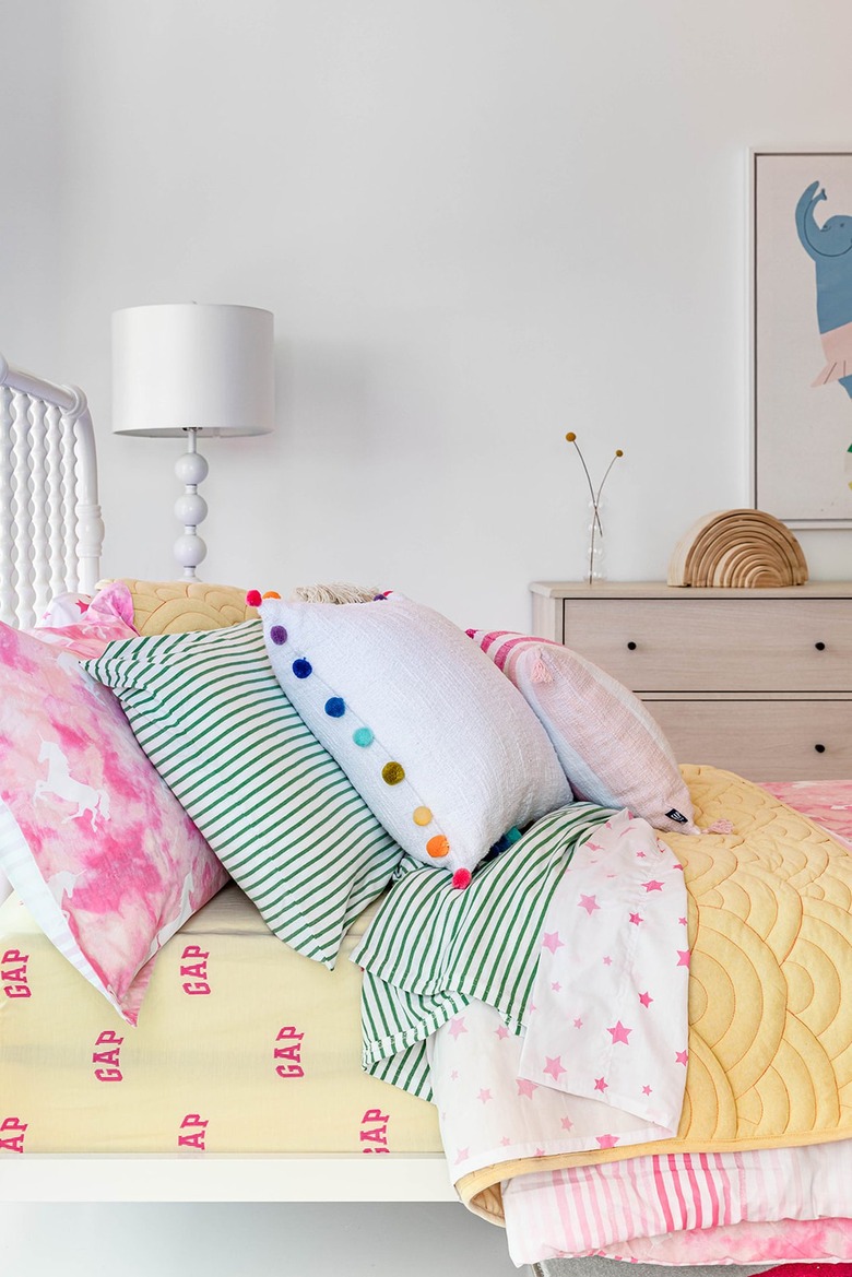 white bed with colorful linens and pillows