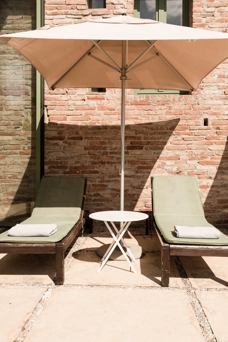 Umbrella and lounge chairs agains red brick wall