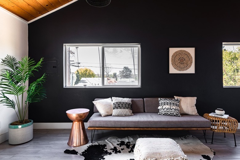 Living room with black-white walls, wood ceiling, gray wood floors, gray-neutral furnishings