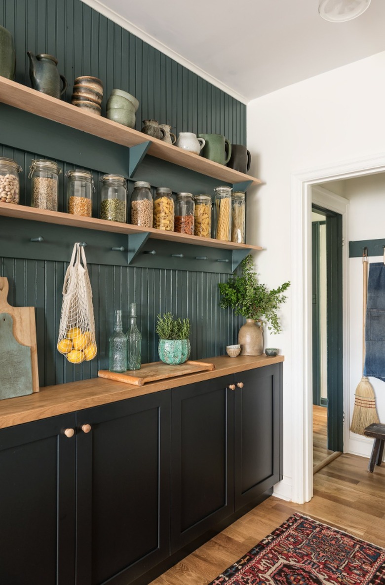 Kitchen with black cabinets and forest green shiplap backsplash.