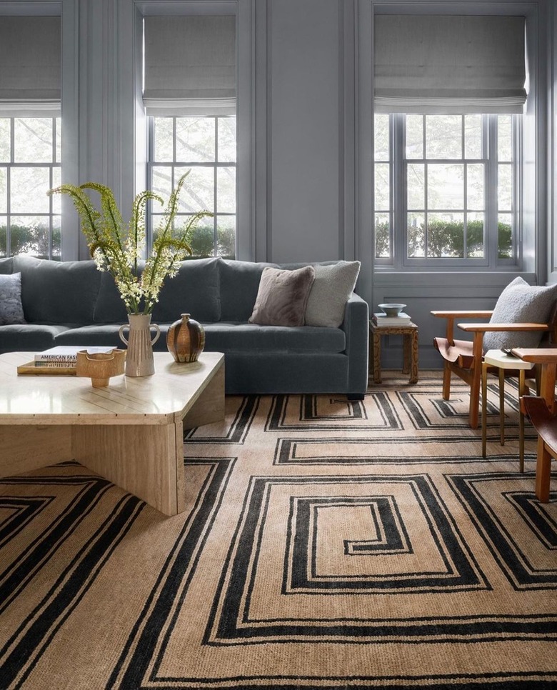 A living room in gray and brown neutrals with a beige travertine coffee table.