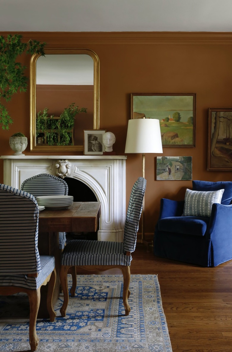 Rust colored walls envelope a dining room with blue and white accents