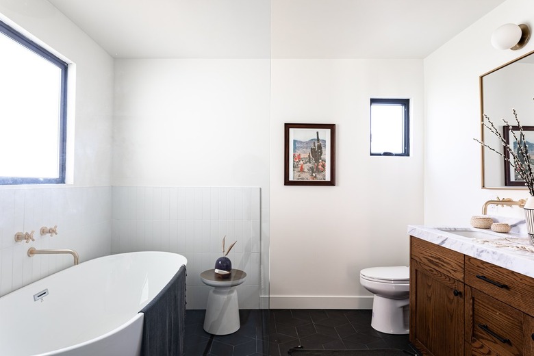 A bathroom with a freestanding tub and wood vanity