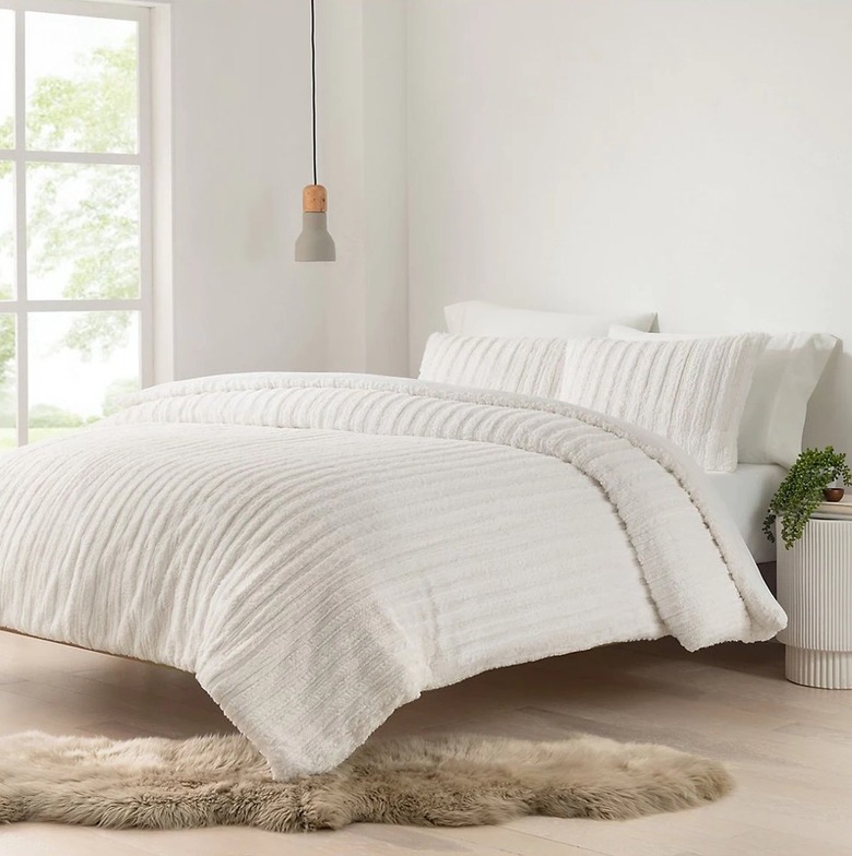 Bedroom with white bedding and fur rug