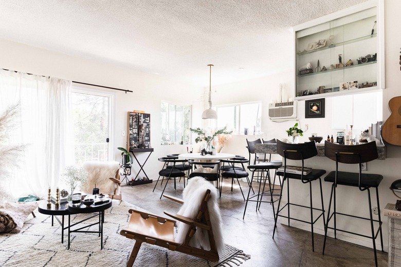 open living space with concrete floors, kitchen, dining table, sheer curtains