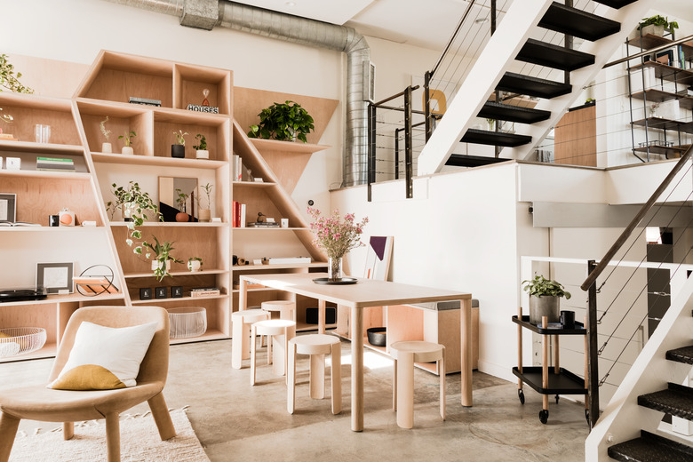 concrete floor in living room with exposed stairs, dining table, bookshelves