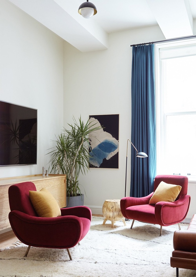 colorful living room with velvet lounge chairs and blue drapery