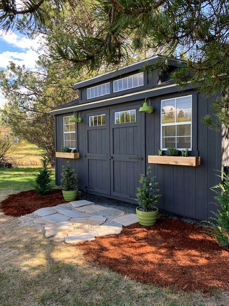 Contemporary shed in black with green barn lights and green planters