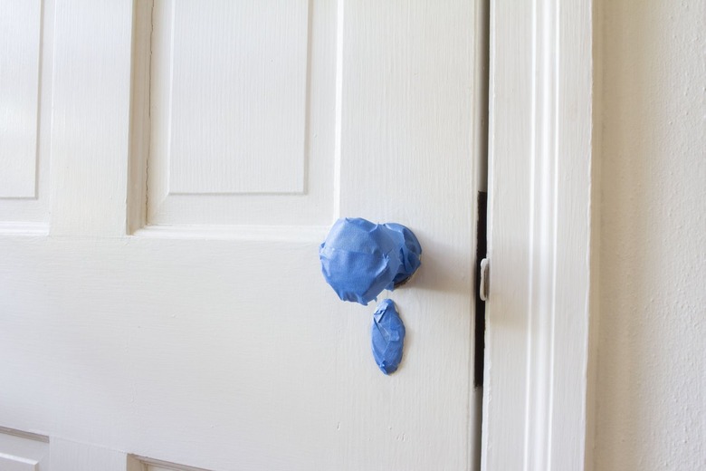 White door wit blue painter's tape on door knob and lock