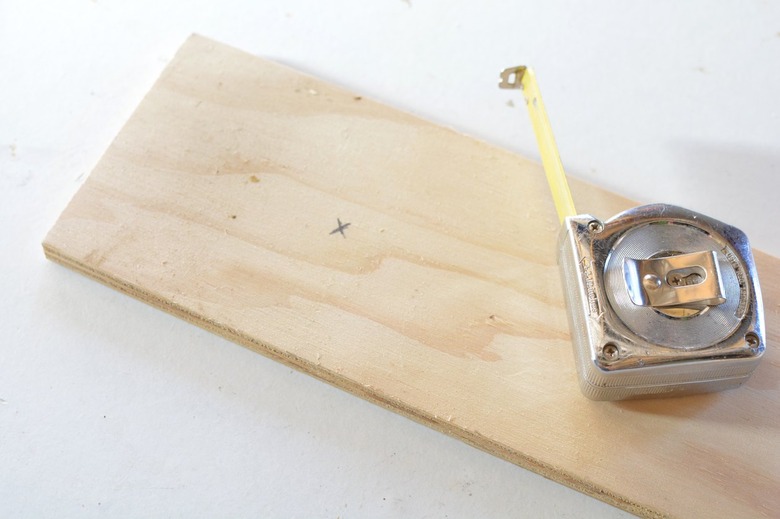 a tape measure sits on top of the base panel with an x penciled on it