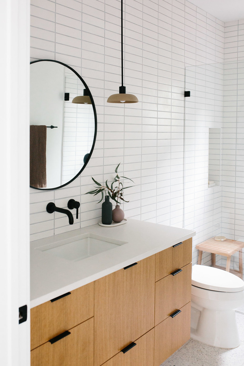 undermount bathroom sink with white wall tile and a wood vanity cabinet