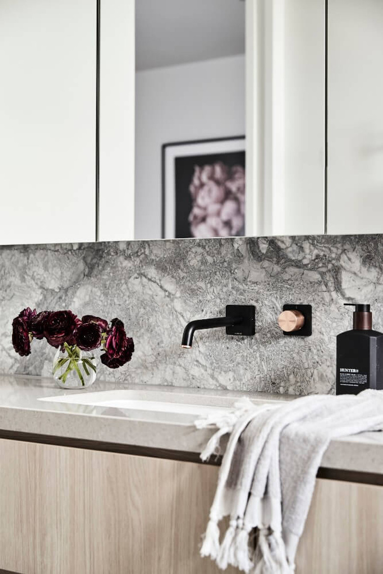 undermount bathroom sink with marble backsplash and light wood vanity