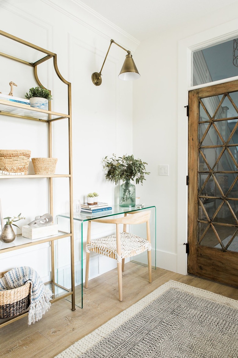 corner home office with glass desk and brass wall sconce