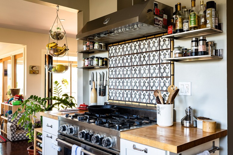 A kitchen with white cabinets with wood countertops and tile backsplash