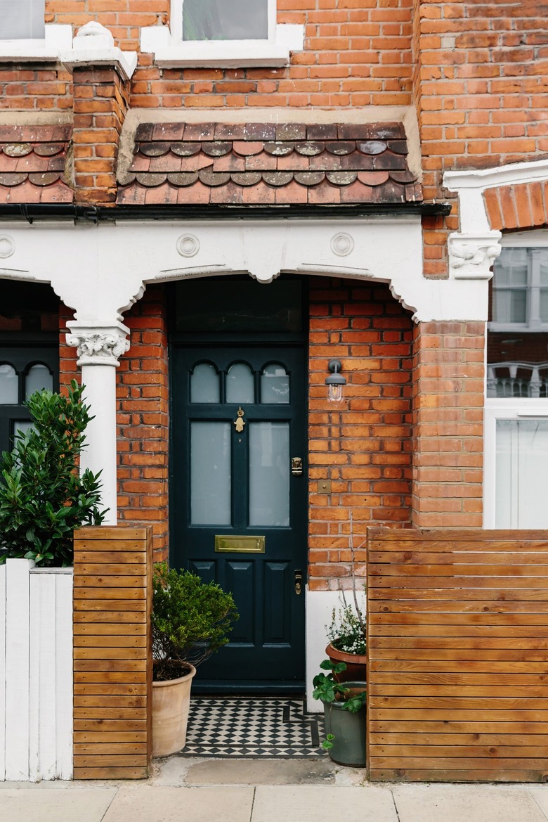 Exterior of front stoop of brick house with green plants and white trim