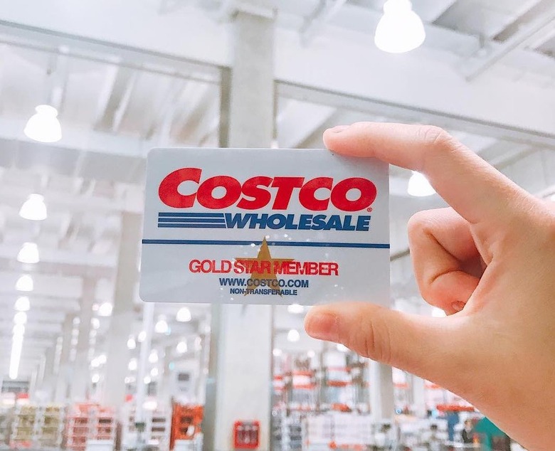 Hand holding up a Costco Gold Star membership card in a Costco store