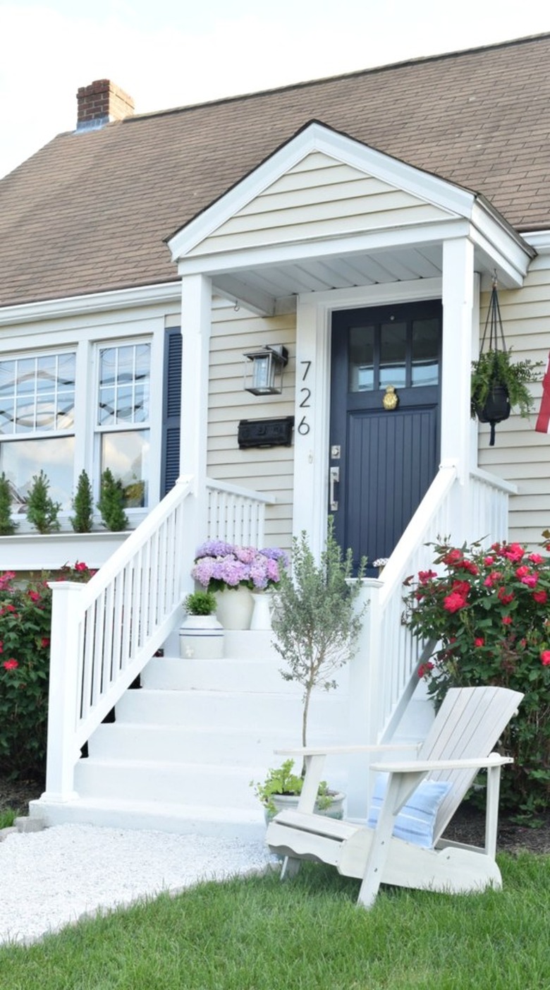 Cream Craftsman home exterior with navy blue front door and white front steps