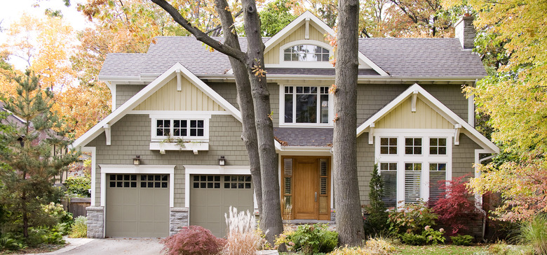 Light green and cream Craftsman home exterior with white trim surrounded by trees