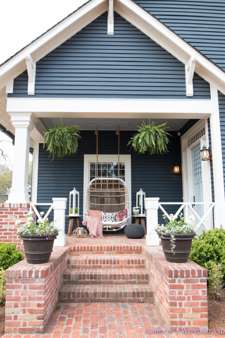 Craftsman front porch with hanging rattan chair and white lanterns