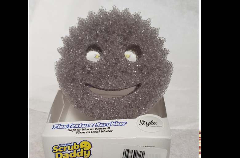 A gray Scrub Daddy smiley face sponge in packaging.