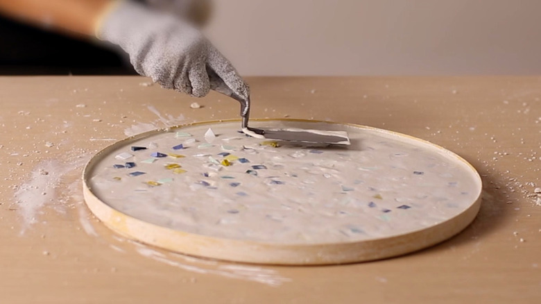 Smoothing layer of glass chips and wet concrete with finishing trowel for terrazzo tabletop