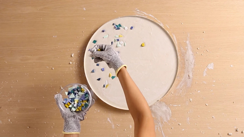 Spreading broken glass tiles over concrete for terrazzo table