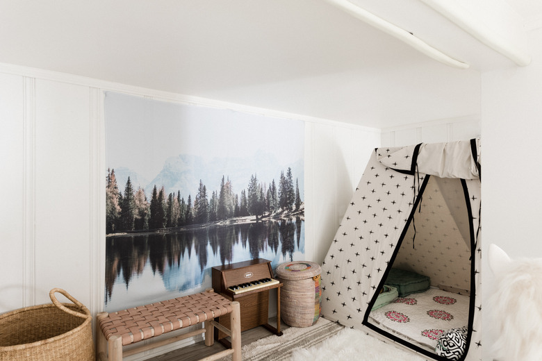 Kids' room with teepee, large canvas of outdoor scene, and toy piano.