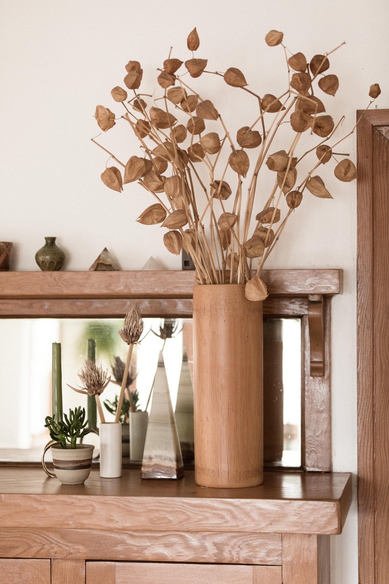 beige vase with dried flowers on a wooden tabletop