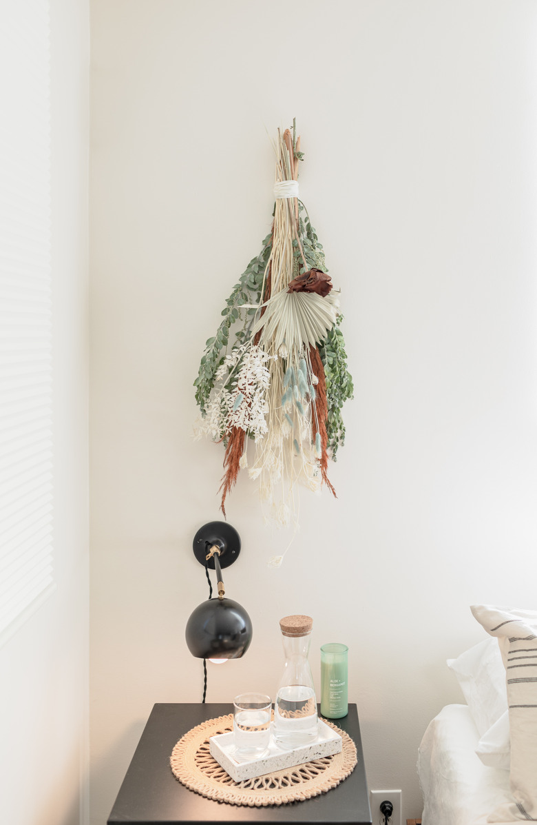 Dried floral arrangement hanging on wall.