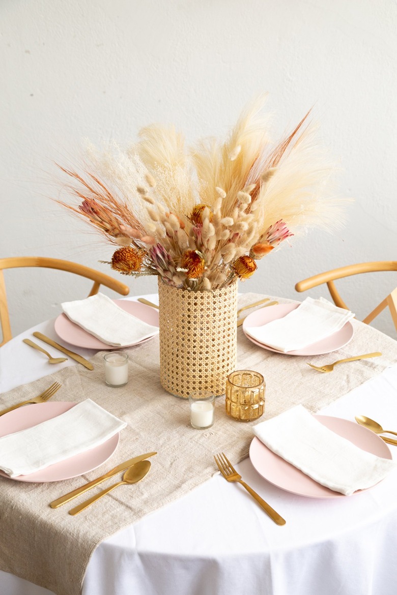 Cane vase with dried flowers and plants on dining table