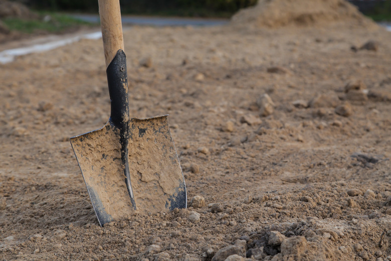 Dirty closeup spade in dry clay soil. View from above. Space for text