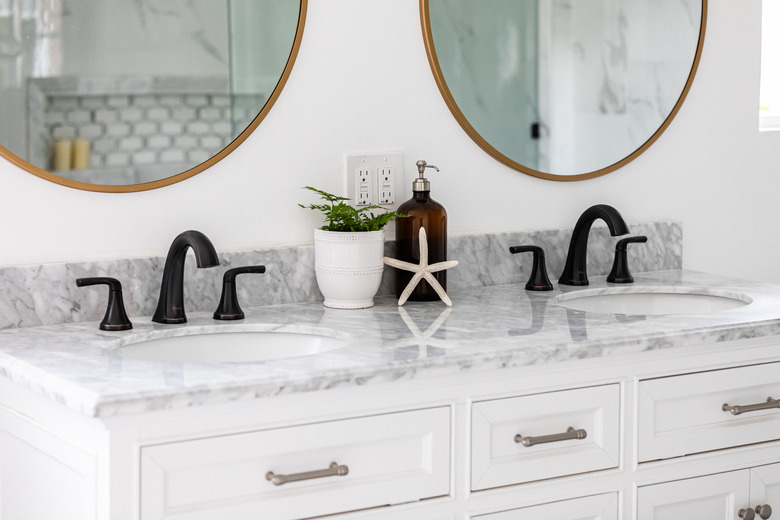 bathroom vanity with two sinks and two circular mirrors