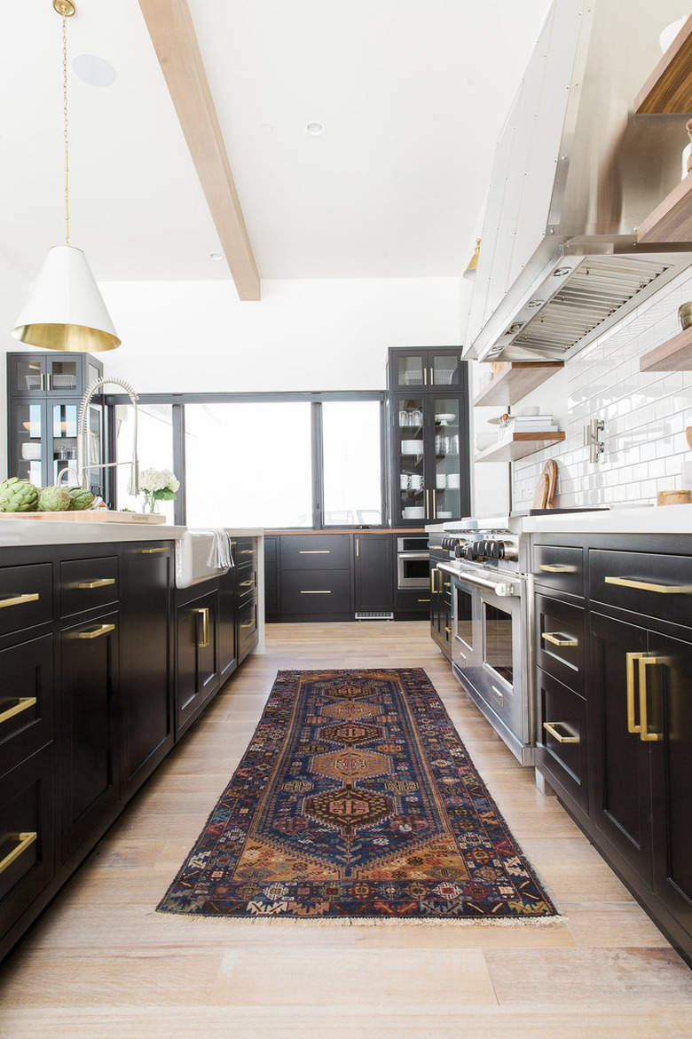 dark kitchen cabinets with light floors with brass hardware and light wood floors