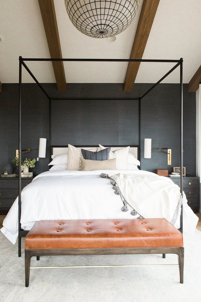 dark minimalist bedroom with brown leather bench and canopy bed,