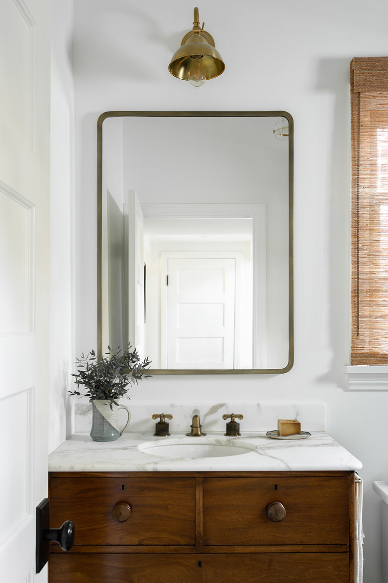 white bathroom with deck-mounted faucet on wood vanity and marble countertop