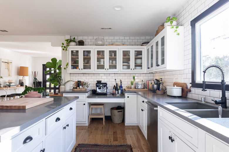 white kitchen cabinets with plants, kitchenware, and more on top