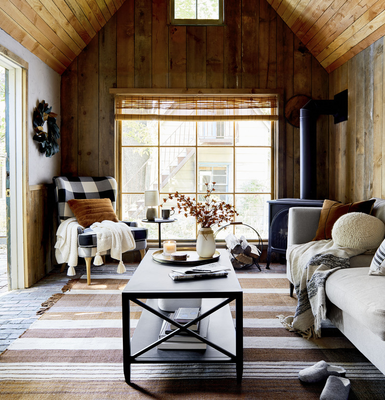 cozy living rooom with wood paneled walls and a buffalo check wingback chair