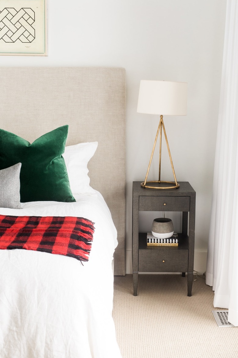 bedroom with red and black tartan throw and green velvet pillows