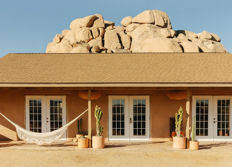 seen from the front, a long terra cotta-tiled, shaded porch with a hammock runs the length of the house