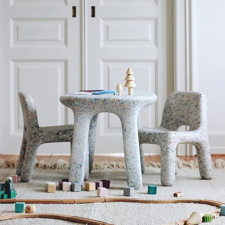 A marble looking small table for a child with two matching chairs in front of white double doors.