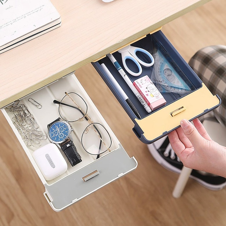 person opening an under-the-desk small drawer, with another drawer next to it, both with desk supplies inside