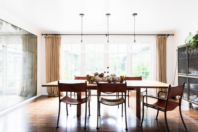 neutral dining room idea with mirrored accent wall and storage cabinet and floor to ceiling drapery