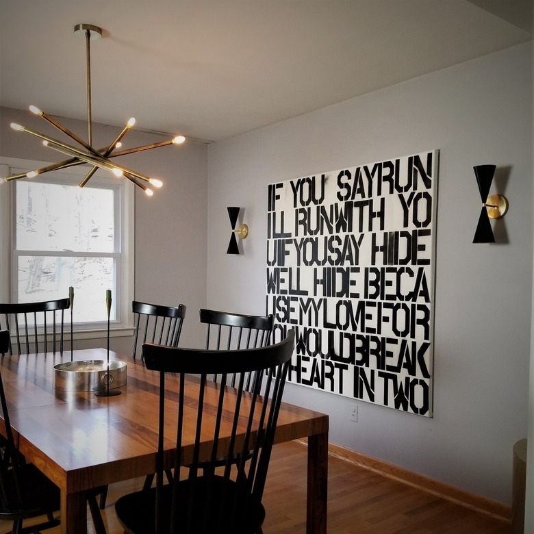 dining room lighting idea with chandelier over table and set of wall sconces next to artwork