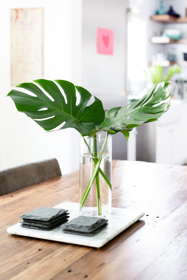 centerpiece tray with two large monstera leaves in simple clear vase